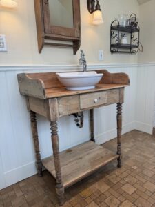 A farmhouse style vanity against a bathroom wall