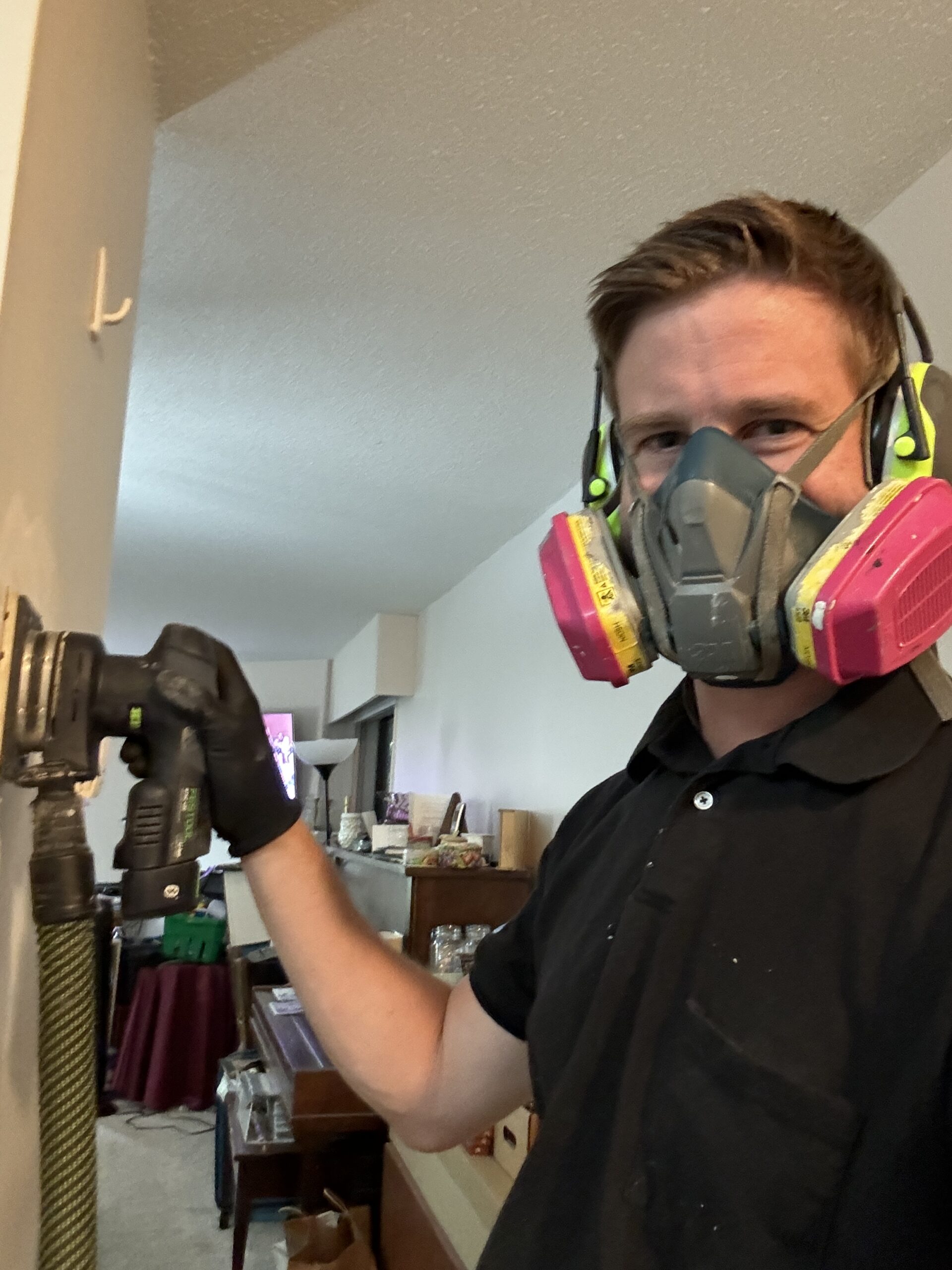 A man sanding a wall